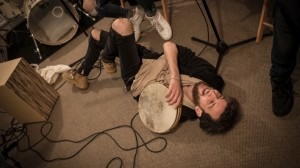 Syrian drummer Ali Hasan lies on the floor laughing during Musiqana’s band practice at the Super Sessions cafe in Berlin. © UNHCR/Daniel Morgan