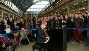  Elton John playing a street piano at St Pancras Station © The Guardian