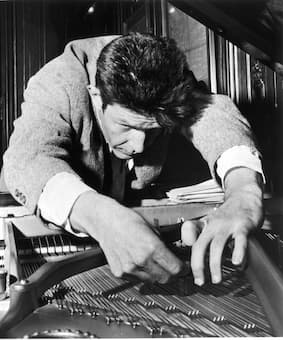 John Cage preparing a piano