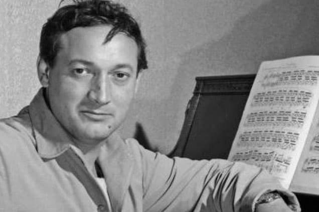 Black and white photo of György Cziffra sitting next to the upright piano