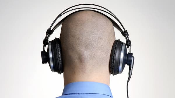 A bald man listening to music with his headphone