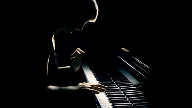 A pianist playing alone in complete darkness