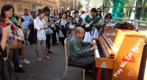 A crowd gathering around a street piano