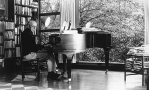 Black and white photo of Aaron Copland playing the piano