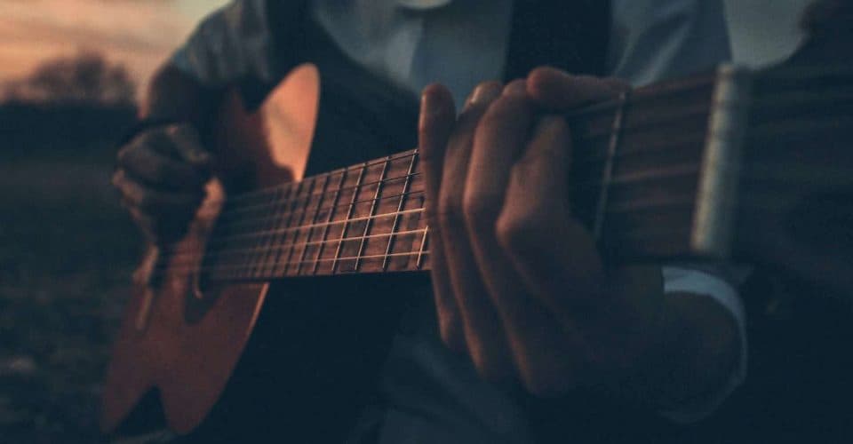 close up photo of a man's hand playing the guitar
