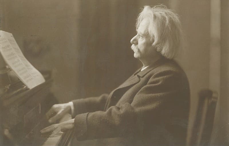 Edvard Grieg with a grand piano, c. 1900